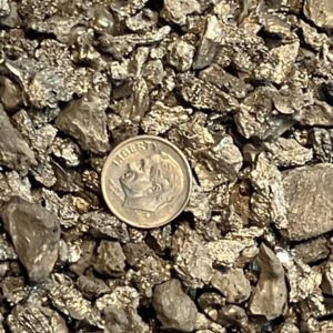 Crushed hafnium ingot pieces under 1 inch, shown with a dime for scale